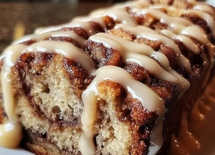 Delicious cinnamon roll banana bread slice with a drizzle of icing