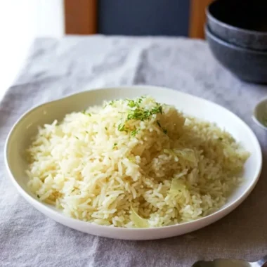 A bowl of fluffy Butter Rice garnished with herbs, showcasing its buttery texture.