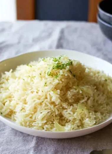 A bowl of fluffy Butter Rice garnished with herbs, showcasing its buttery texture.