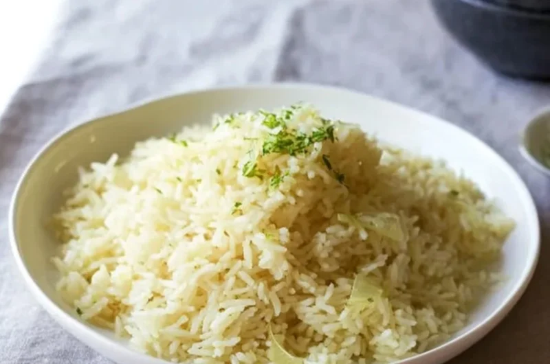 A bowl of fluffy Butter Rice garnished with herbs, showcasing its buttery texture.