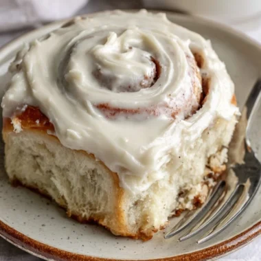 Freshly baked cinnamon rolls topped with creamy icing on a wooden surface.
