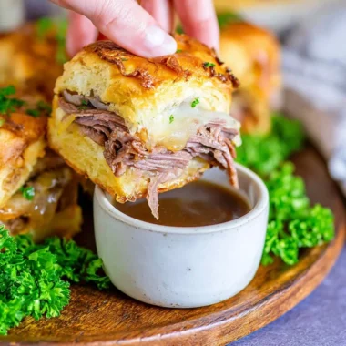 Delicious French Dip Sliders served on a platter with dipping sauce.