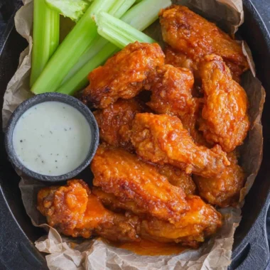 Plate of homemade buffalo wings with a spicy sauce and celery sticks