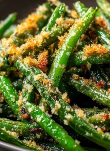 Plate of roasted green beans with garlic and parmesan on a wooden table