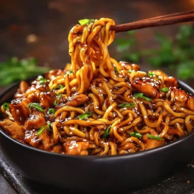 Delicious sticky garlic chicken served over noodles in a vibrant dish.