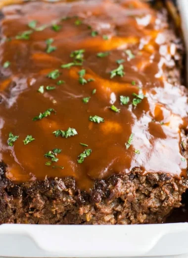 Delicious classic meatloaf served with brown gravy on a plate.