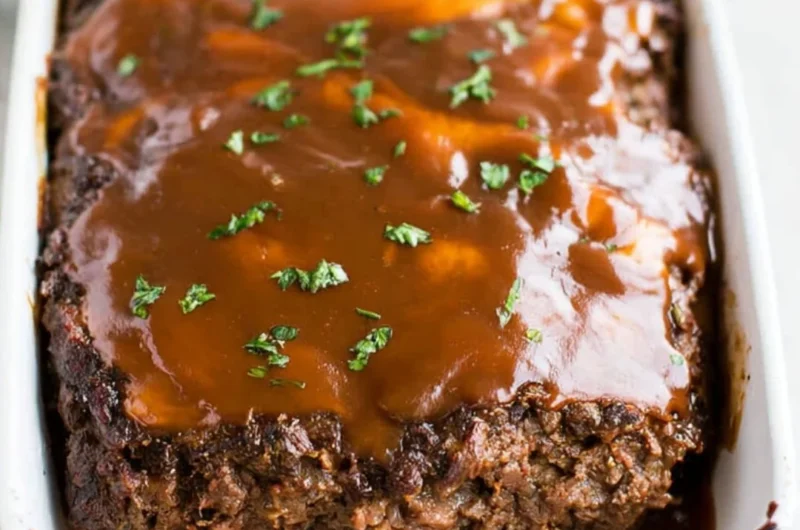 Delicious classic meatloaf served with brown gravy on a plate.