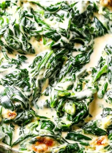Creamed spinach served in a bowl, garnished with herbs.