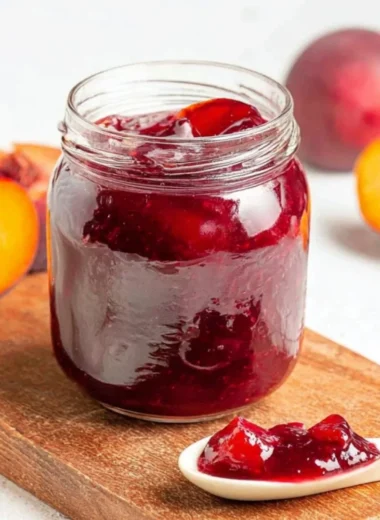 Jar of homemade easy plum jam on a wooden table