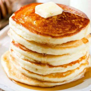 Stack of fluffy pancakes topped with syrup and fresh berries