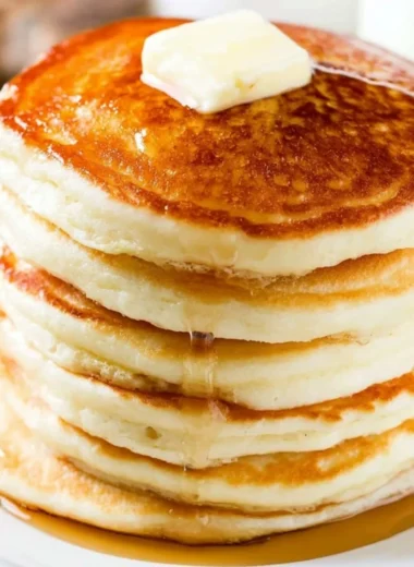 Stack of fluffy pancakes topped with syrup and fresh berries