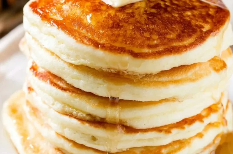 Stack of fluffy pancakes topped with syrup and fresh berries