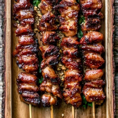 Grilled Thai Coconut Chicken Skewers served with dipping sauce and fresh herbs.