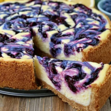 Slice of lemon blueberry cheesecake topped with fresh blueberries on a plate.