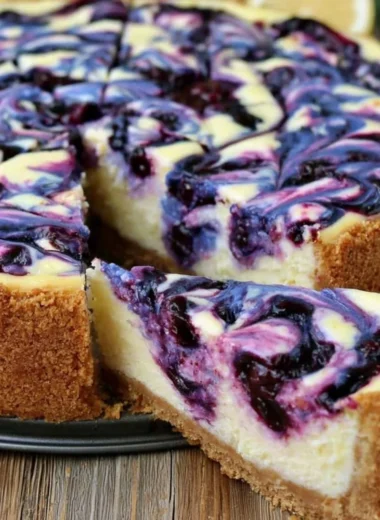 Slice of lemon blueberry cheesecake topped with fresh blueberries on a plate.
