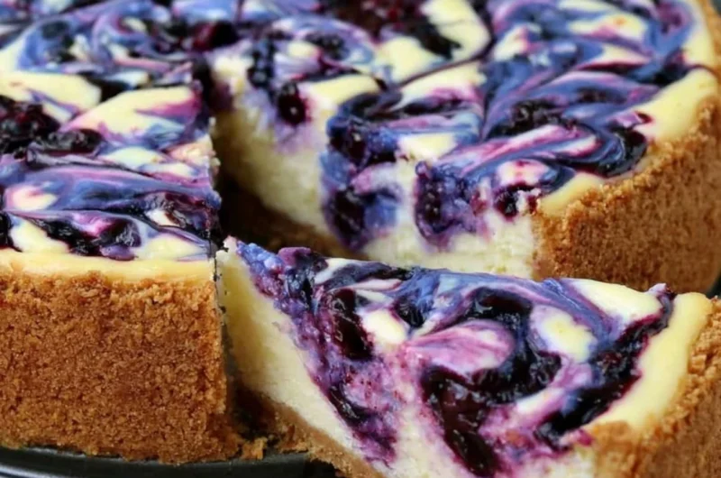 Slice of lemon blueberry cheesecake topped with fresh blueberries on a plate.