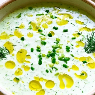 Chilled cucumber gazpacho soup garnished with fresh herbs and vegetables.
