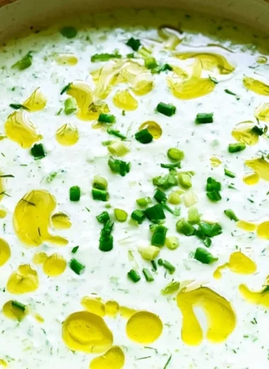 Chilled cucumber gazpacho soup garnished with fresh herbs and vegetables.