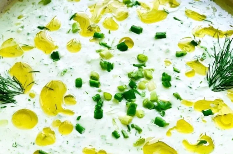 Chilled cucumber gazpacho soup garnished with fresh herbs and vegetables.