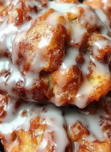 Freshly baked soft cinnamon apple fritters topped with powdered sugar.