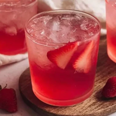 Homemade strawberry iced tea in a glass with fresh strawberries and mint