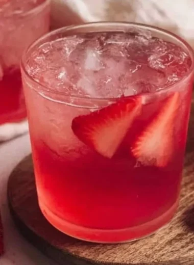 Homemade strawberry iced tea in a glass with fresh strawberries and mint