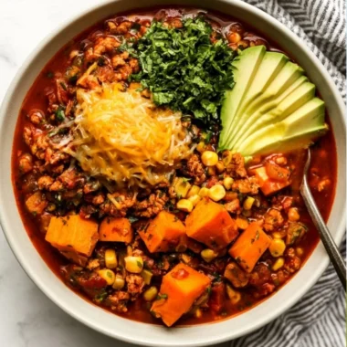 Bowl of sweet potato turkey chili topped with fresh cilantro and diced avocado.