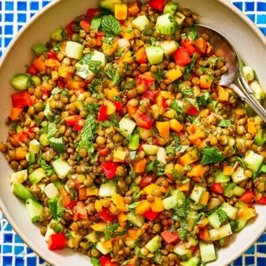A colorful Mediterranean lentil salad with fresh vegetables and herbs in a bowl.