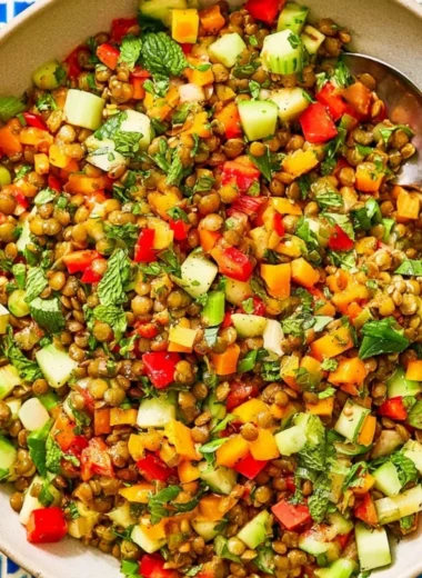 A colorful Mediterranean lentil salad with fresh vegetables and herbs in a bowl.