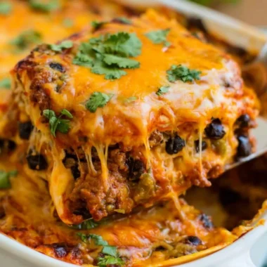 Cozy beef enchilada casserole in a baking dish, topped with cheese and garnished.