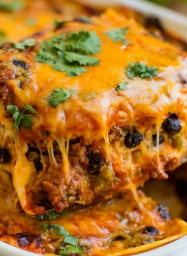 Cozy beef enchilada casserole in a baking dish, topped with cheese and garnished.