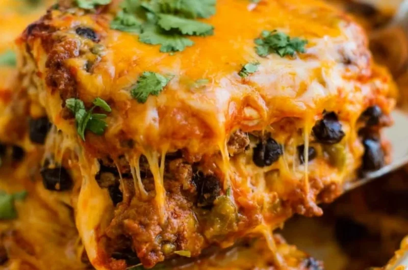 Cozy beef enchilada casserole in a baking dish, topped with cheese and garnished.