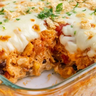 Delicious cozy cheesy chicken taco casserole in a baking dish topped with cheese.