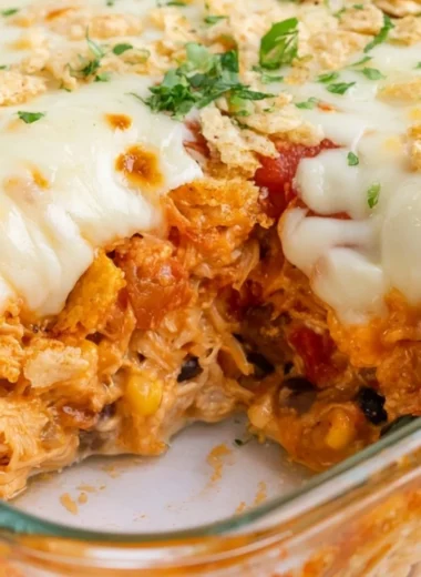 Delicious cozy cheesy chicken taco casserole in a baking dish topped with cheese.
