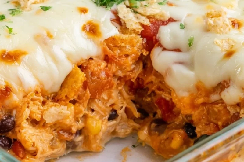 Delicious cozy cheesy chicken taco casserole in a baking dish topped with cheese.