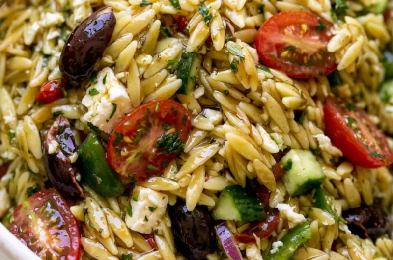 A vibrant bowl of cozy Greek Orzo Salad with vegetables and feta cheese.
