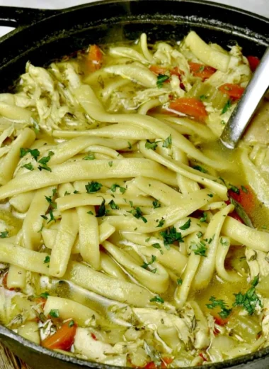 Bowl of cozy homemade chicken noodle soup with vegetables and herbs