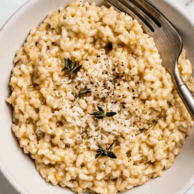 Bowl of creamy risotto topped with fresh herbs and Parmesan cheese