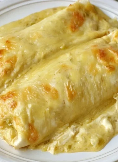 Creamy white chicken enchiladas topped with cheese and sauce