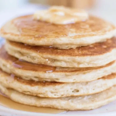 Fluffy sourdough pancakes served with syrup and berries on a plate