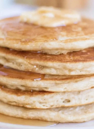 Fluffy sourdough pancakes served with syrup and berries on a plate