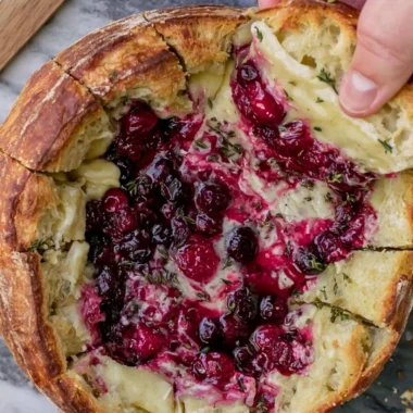 Baked cranberry brie bread bowl served warm with toppings