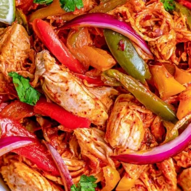 Crockpot chicken fajitas served in a colorful dish with peppers and onions.
