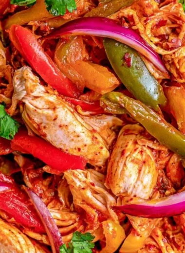 Crockpot chicken fajitas served in a colorful dish with peppers and onions.