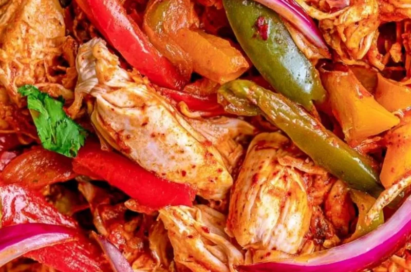 Crockpot chicken fajitas served in a colorful dish with peppers and onions.